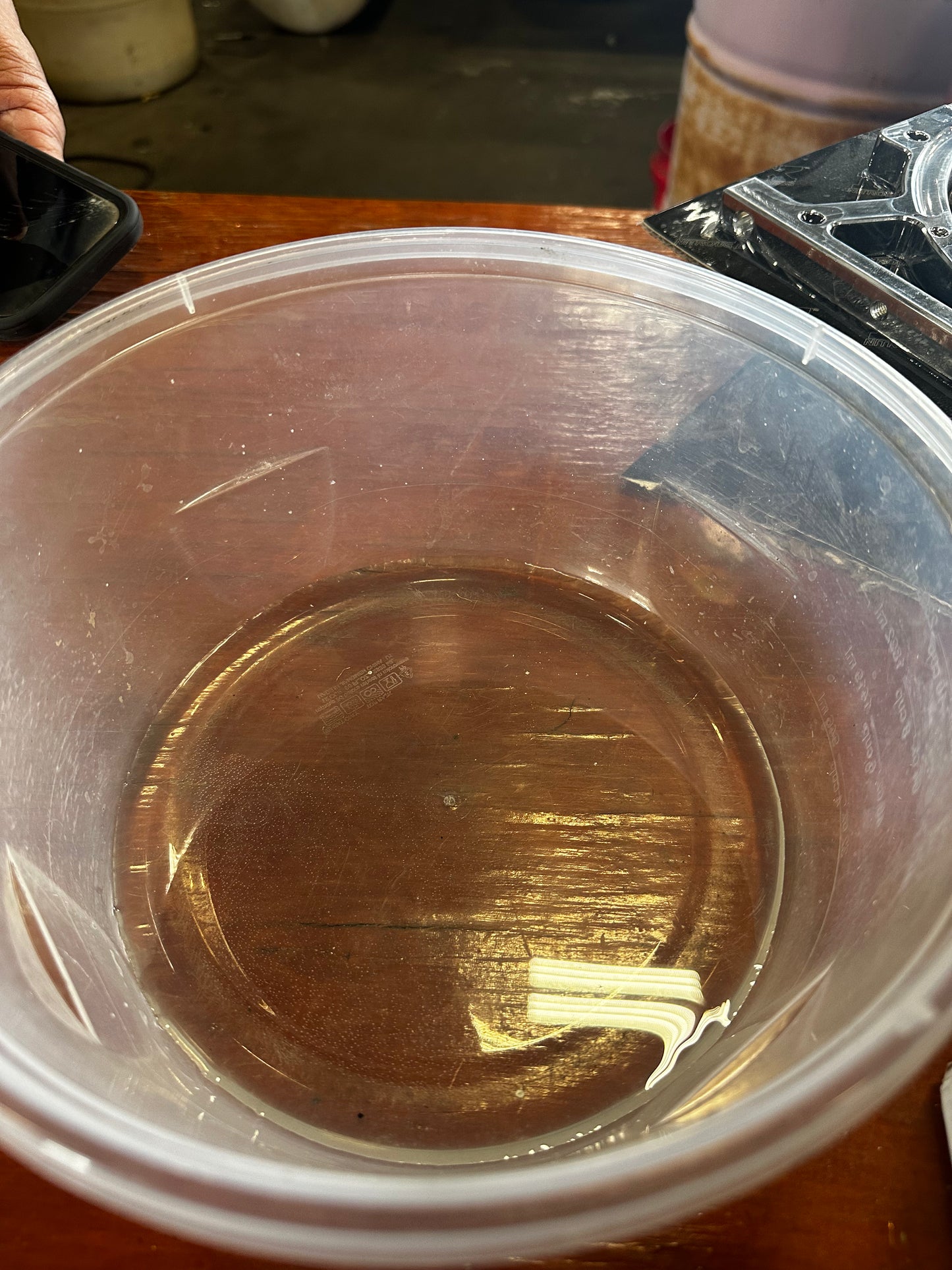Clear plastic container with a small amount of liquid on a wooden surface